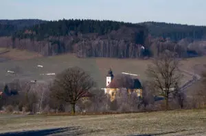 Klidná česká krajina s kostelíkem obklopeným ojíněnými stromy a hlubokými lesy, symbolizující ztišení, samotu a duchovní klid. Foto: Miroslav Neumaier – Tvoje příběhy.