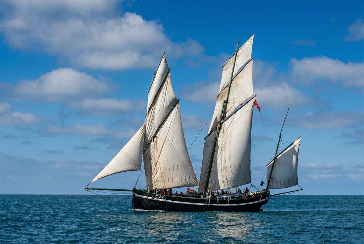 Tradiční třístěžňový lugger na širém moři pod jasnou oblohou